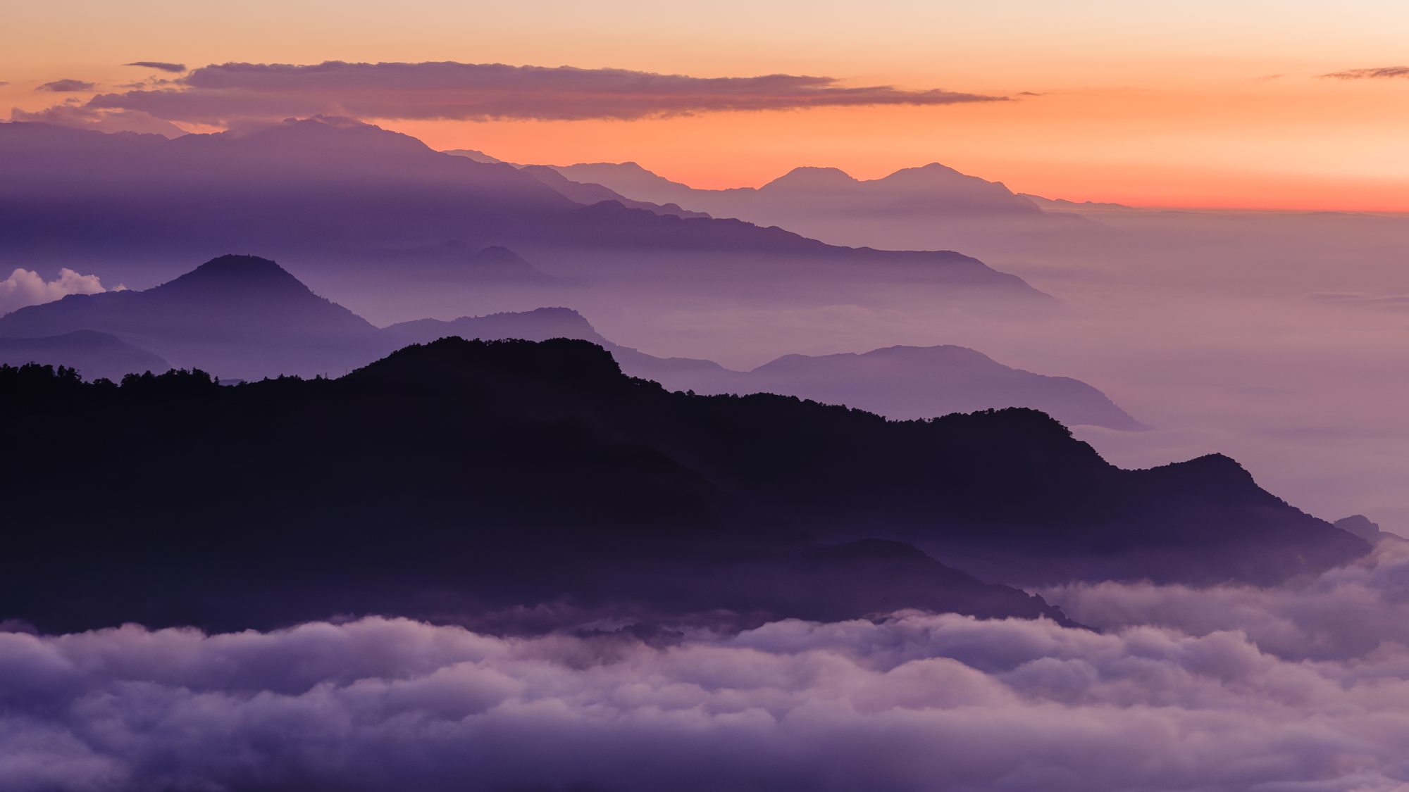 合歡山雲海，層巒沒入晨霧，天際一抹朱紅